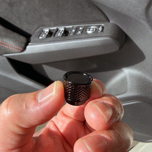 A hand holding a STRIX Gloss Black radio knob for a Honda Civic 9" infotainment in front of a car interior door panel with silver controls.